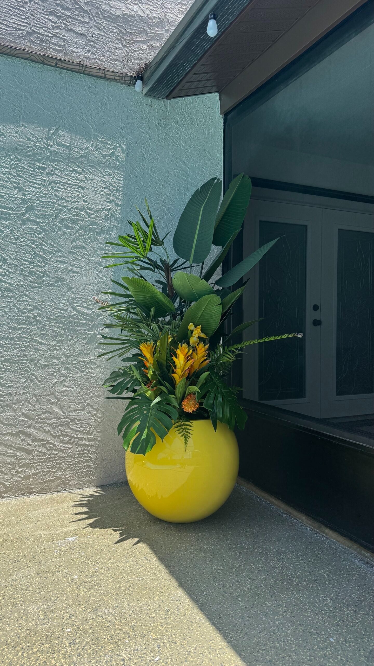 Tropische Mix-Dekoration in einem gelben runden Pflanzgefäß