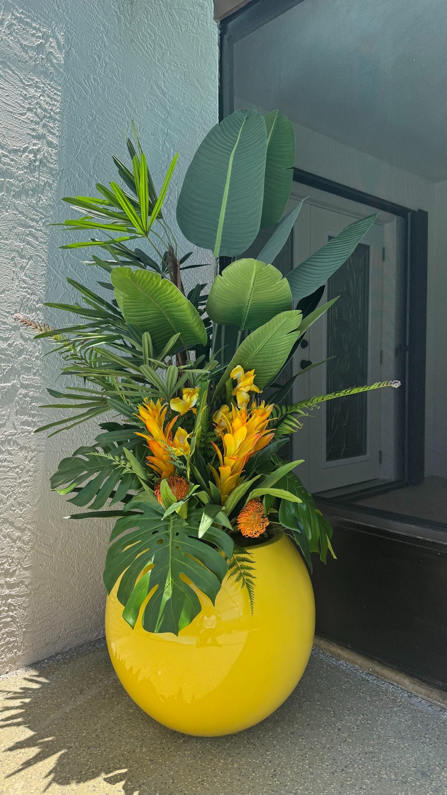 Tropische Mix-Dekoration in einem gelben runden Pflanzgefäß